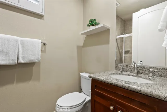 a bathroom with a granite countertop toilet sink and mirror
