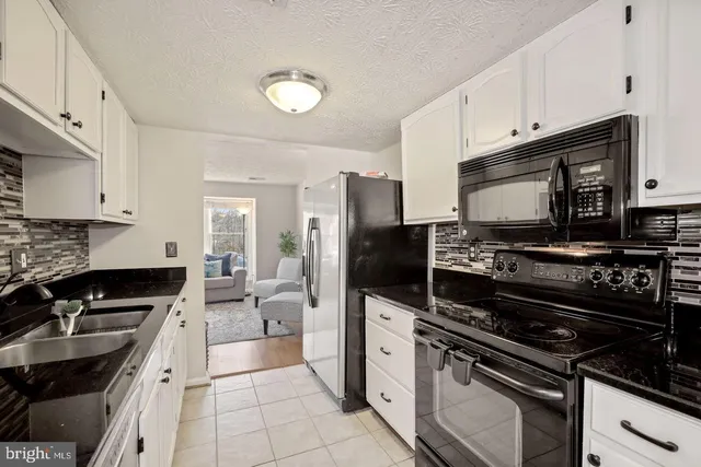 a kitchen with granite countertop white cabinets and stainless steel appliances