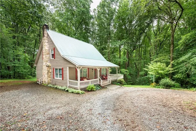 a view of a house with a yard and large trees