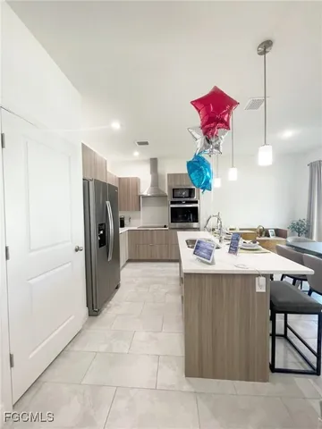 a kitchen with stainless steel appliances kitchen island granite countertop a refrigerator a stove and a sink