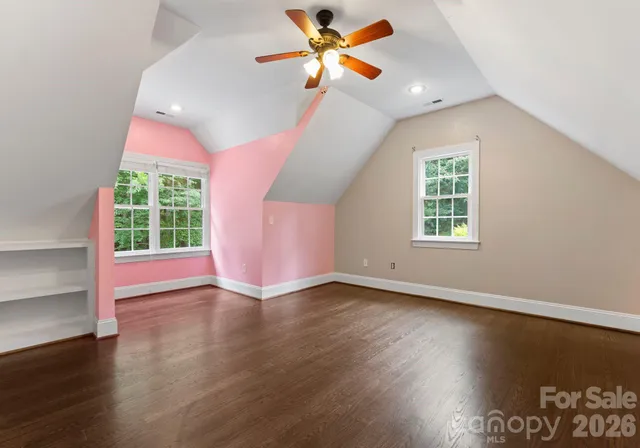 a view of a livingroom with a fireplace a ceiling fan and windows