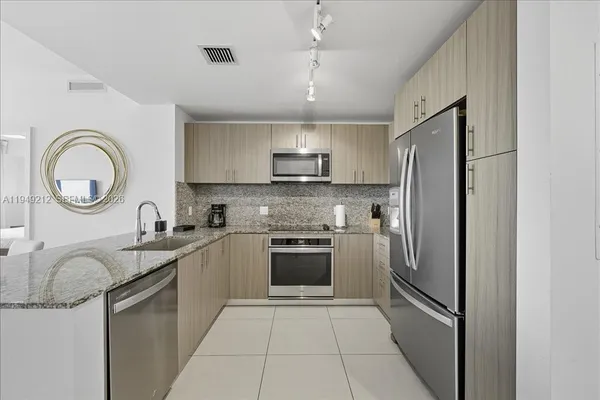 a kitchen with stainless steel appliances granite countertop a refrigerator a sink and a stove
