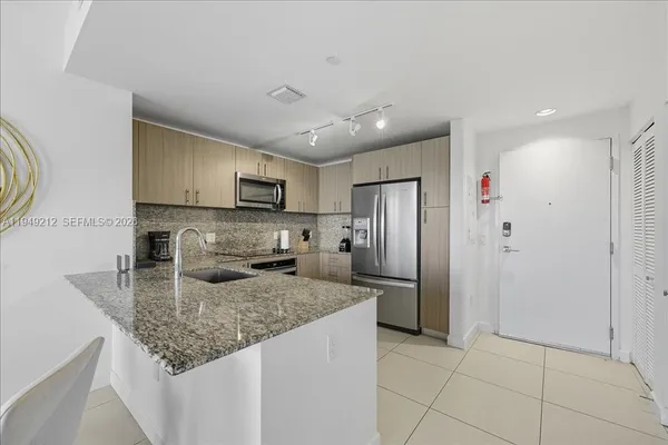 a kitchen with stainless steel appliances granite countertop a sink refrigerator and microwave