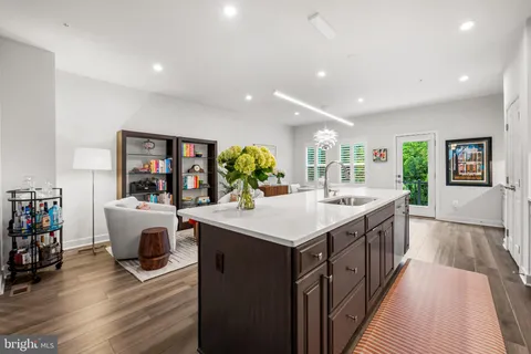 a kitchen with kitchen island a white counter top space a sink wooden floor and a window
