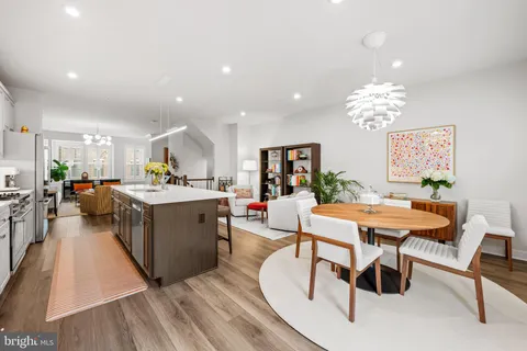 a living room with furniture a chandelier and a kitchen view