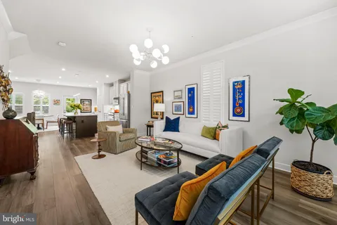a living room with furniture kitchen view and a chandelier
