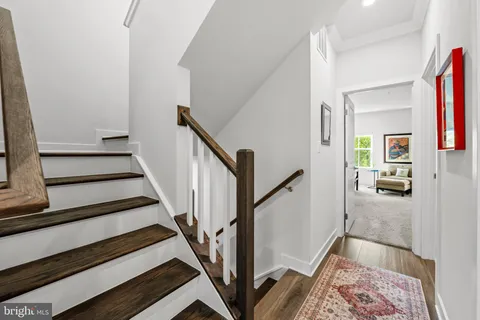 a view of a hallway to a livingroom with wooden floor and furniture