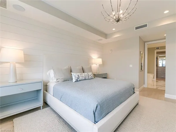 a bedroom with a large bed and a chandelier fan