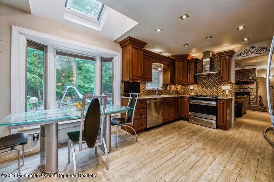 57 Millay Road Morganville, NJ 07751 - Photo 12 of 46 a kitchen with stainless steel appliances granite countertop a stove top oven a sink dishwasher a dining table and chairs with wooden floor