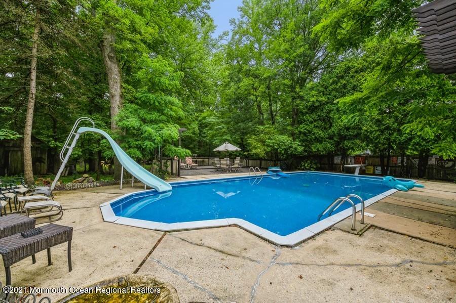 57 Millay Road Morganville, NJ 07751 - Photo 32 of 46 a view of swimming pool with lounge chair and dinning table under an umbrella