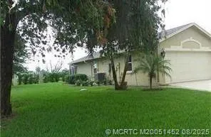 a view of a white house with a big yard and large trees