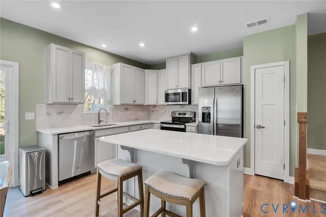 a kitchen with stainless steel appliances a sink a stove a refrigerator cabinets and wooden floor