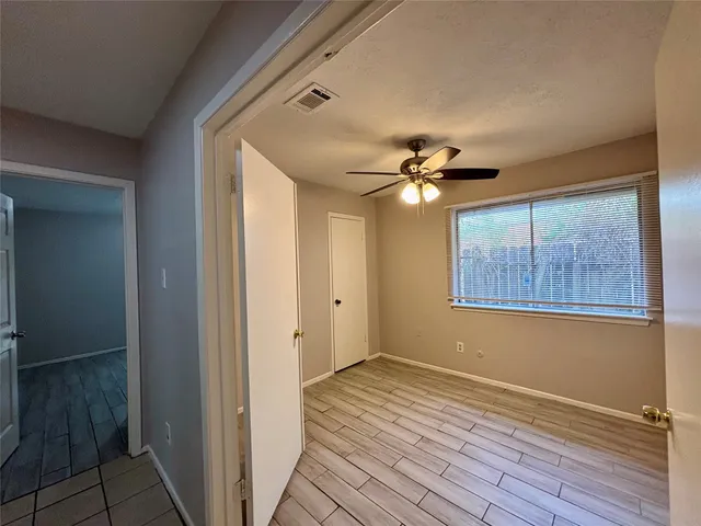 a view of a livingroom with wooden floor a ceiling fan and windows