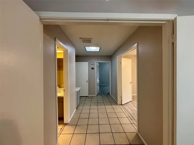a view of a hallway with wooden floor and a bathroom