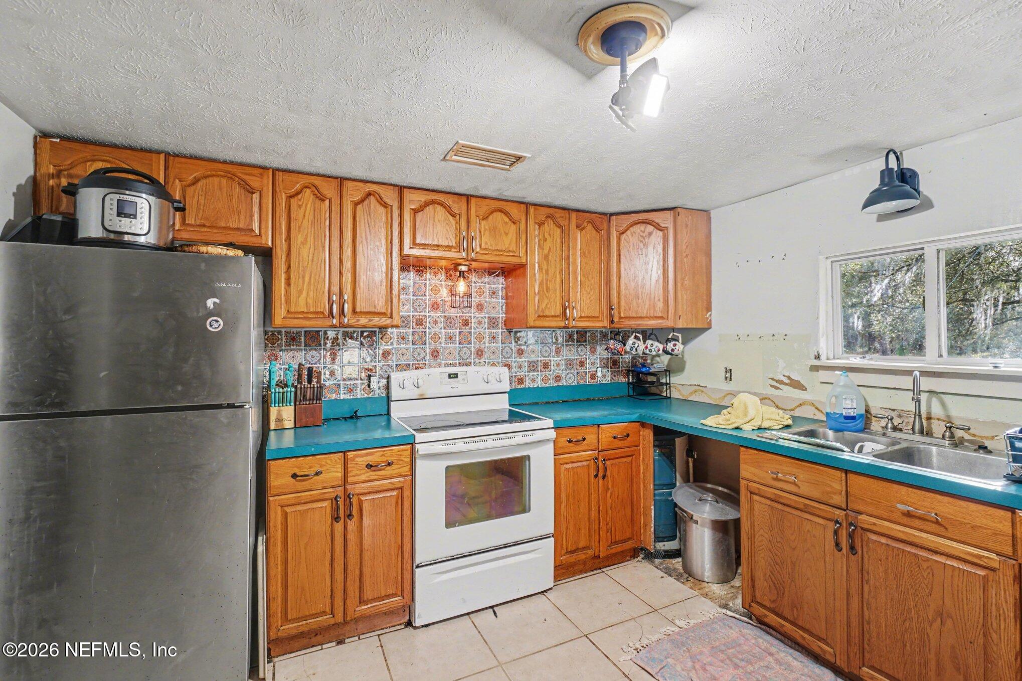 3390 Lannie Road Jacksonville, FL 32218 - Photo 3 of 18 a kitchen with stainless steel appliances granite countertop a refrigerator a sink dishwasher a stove with white cabinets and wooden floor