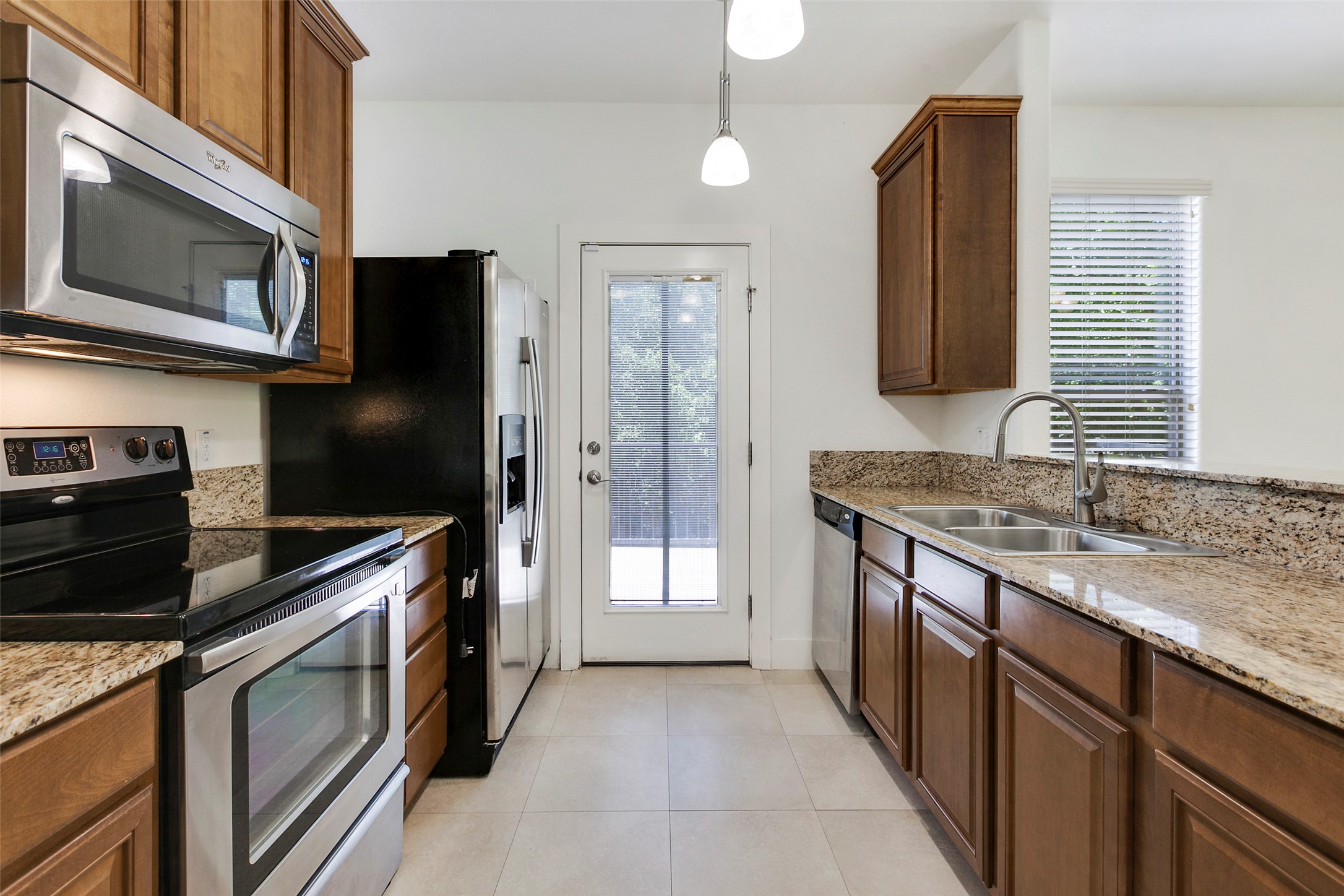 13420 Lyndhurst Street, Unit 308 Austin, TX 78717 - Photo 14 of 25 Kitchen featuring stainless steel appliances, light stone counters, decorative light fixtures, and light tile patterned floors