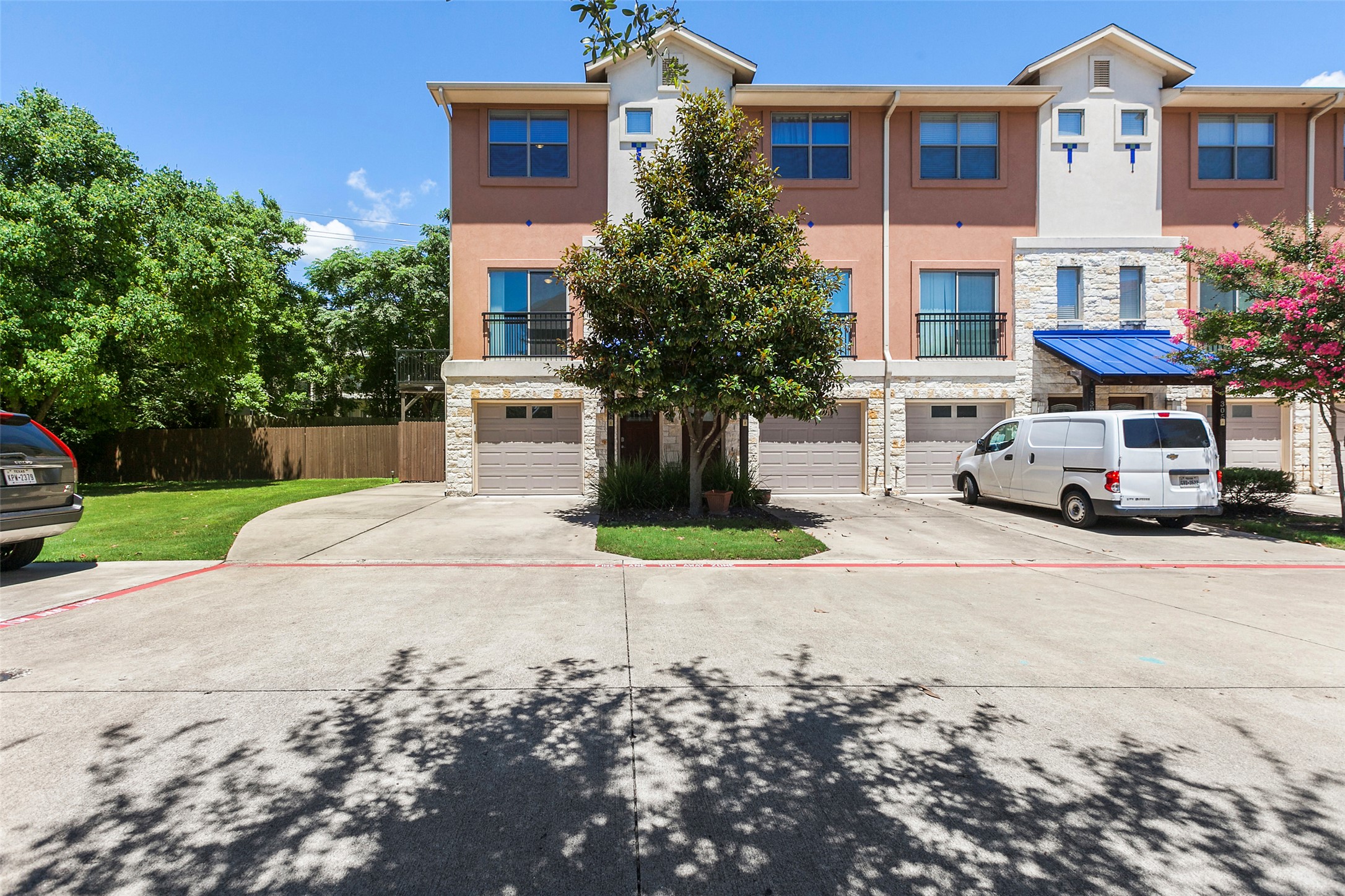 13420 Lyndhurst Street, Unit 308 Austin, TX 78717 - Photo 4 of 25 View of front of house featuring stone siding, stucco siding, driveway, a garage, and a balcony