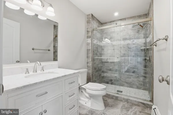 a bathroom with a shower sink vanity mirror and toilet