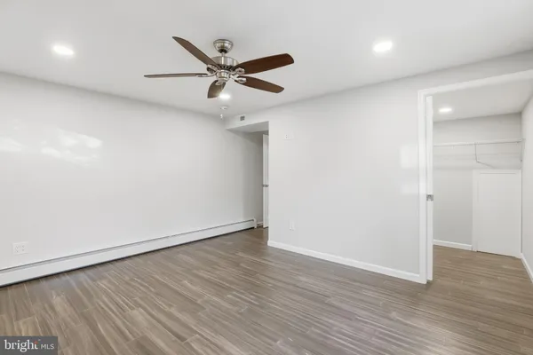 an empty room with wooden floor fan and windows