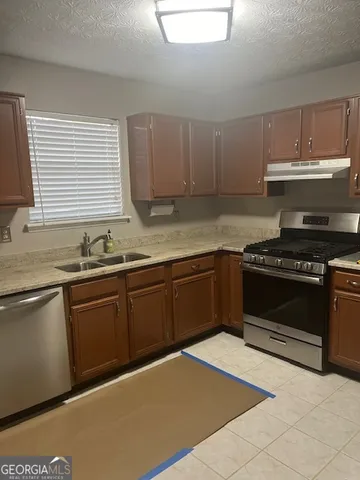 a kitchen with granite countertop a stove a sink and dishwasher wooden cabinets