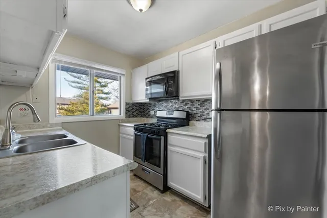 a kitchen with granite countertop a sink stainless steel appliances and window