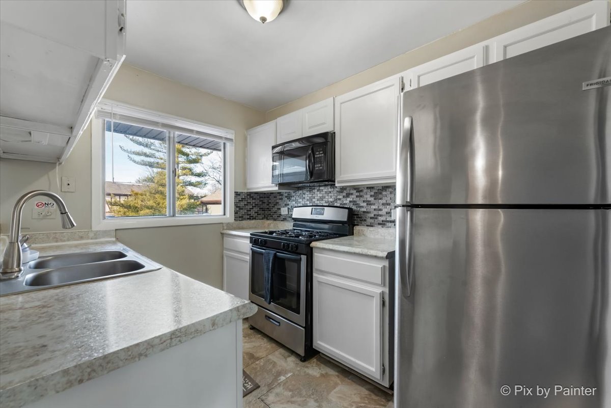 6207 Kit Carson Drive, Unit 6207 Hanover Park, IL 60133 - Photo 6 of 24 a kitchen with granite countertop a sink stainless steel appliances and window