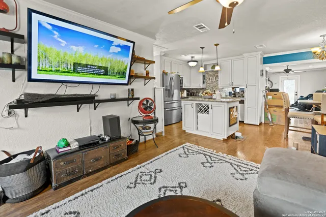 a living room with stainless steel appliances kitchen island furniture and a flat screen tv