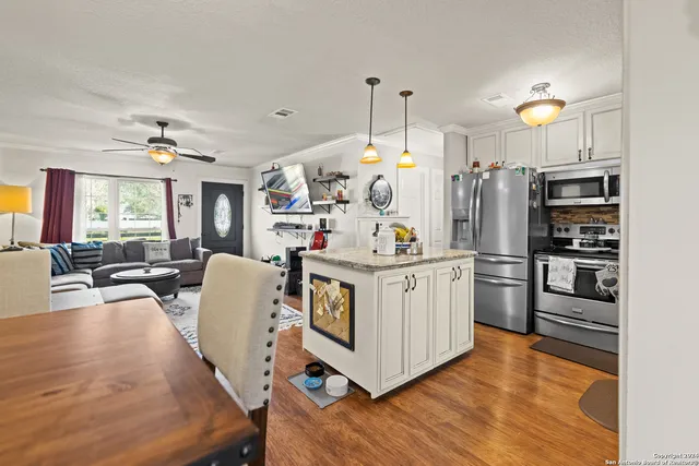 a kitchen that has a lot of white cabinets and stainless steel appliances