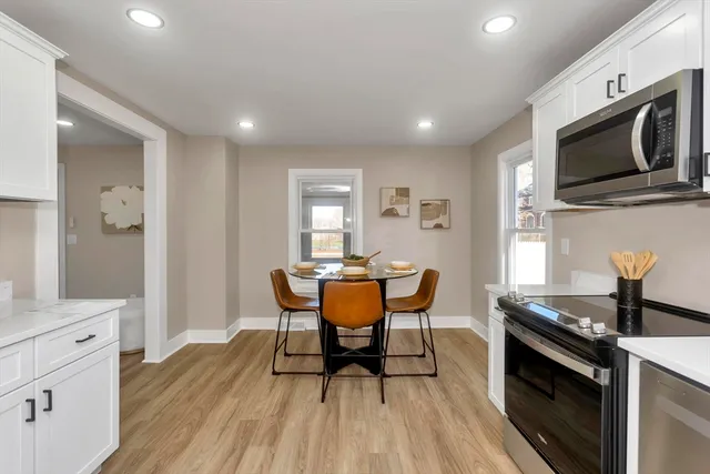 a kitchen with stainless steel appliances granite countertop a stove top oven a sink dishwasher a dining table and chairs with wooden floor