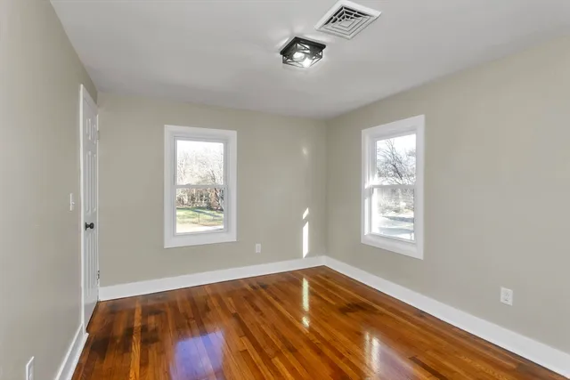 a view of an empty room with a window and wooden floor