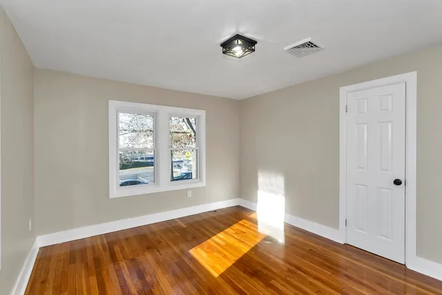 a view of an empty room with a window and wooden floor