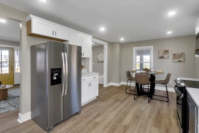 a kitchen with stainless steel appliances a refrigerator a table and chairs