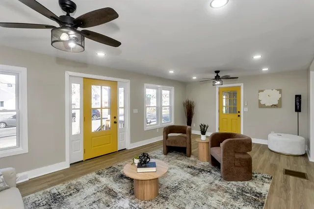 a living room with furniture a chandelier fan and a window