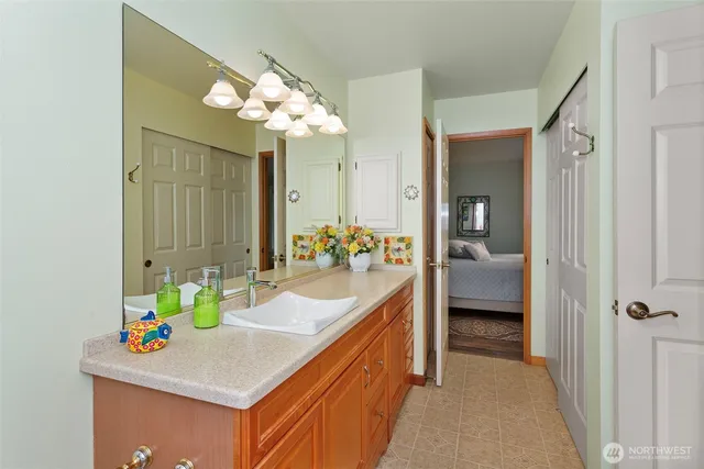 a bathroom with a sink vanity granite tub and a mirror