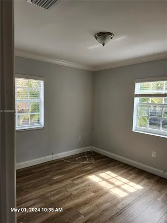 a view of empty room with wooden floor and fan