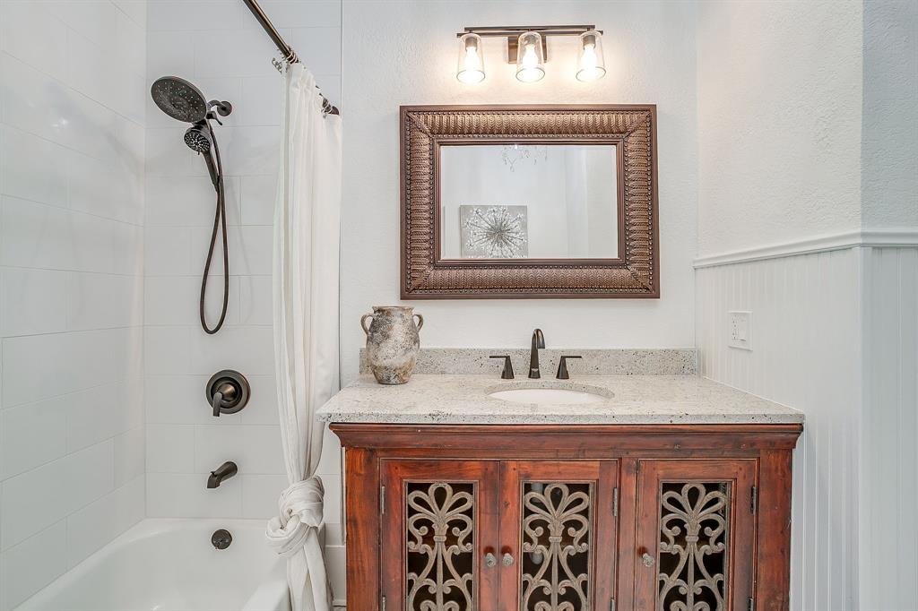 116 East Akard Street Weatherford, TX 76086 - Photo 19 of 32 a bathroom with a granite countertop sink a mirror a vanity and a bathtub