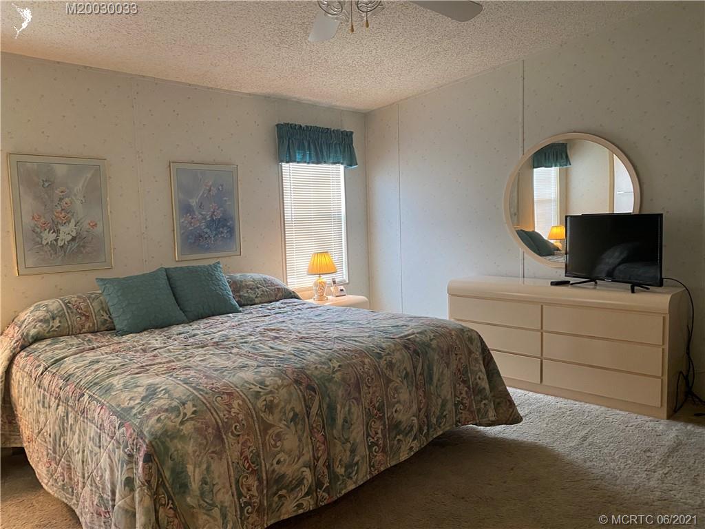 4718 Southeast Balsawood Terrace Stuart, FL 34997 - Photo 14 of 25 a bedroom with a bed and a flat screen tv