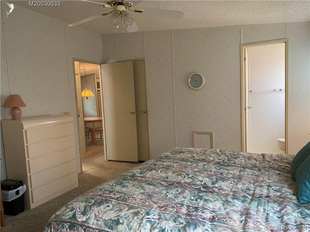 4718 Southeast Balsawood Terrace Stuart, FL 34997 - Photo 16 of 25 a bedroom with a bed and a chandelier