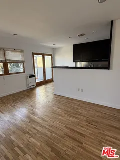 a view of an empty room with window and wooden floor