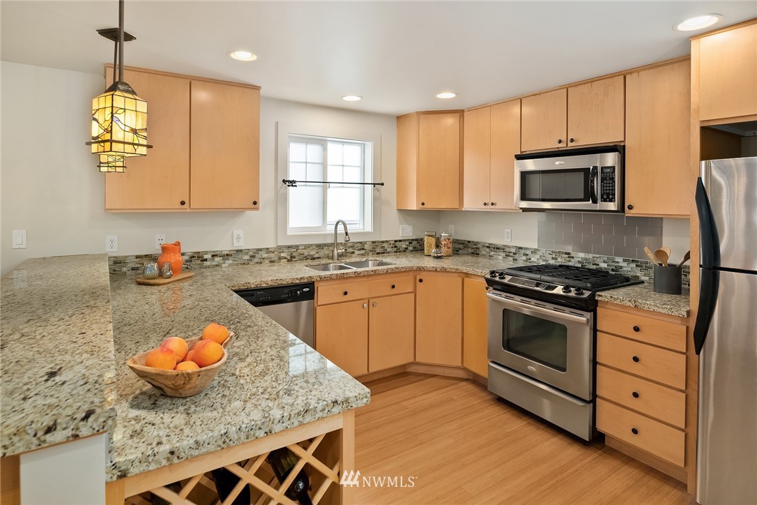 723 North 95th Street, Unit B Seattle, WA 98103 - Photo 4 of 24 a kitchen with stainless steel appliances granite countertop a stove a sink and a microwave