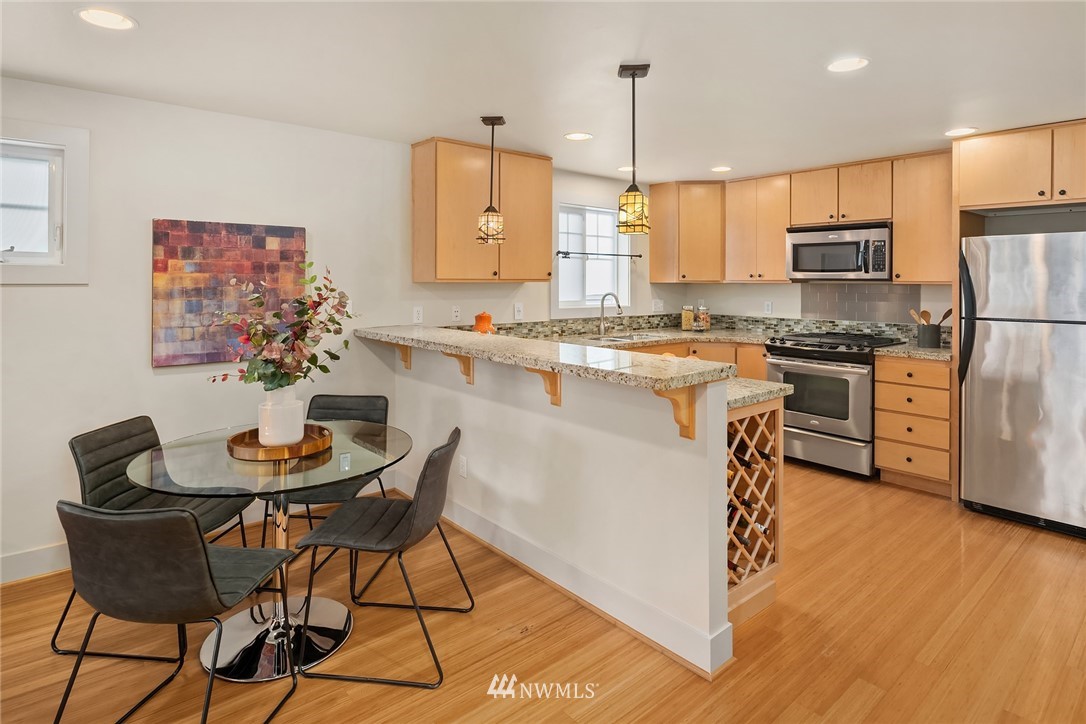 723 North 95th Street, Unit B Seattle, WA 98103 - Photo 6 of 24 a kitchen with stainless steel appliances granite countertop a stove a sink a microwave a dining table and chairs