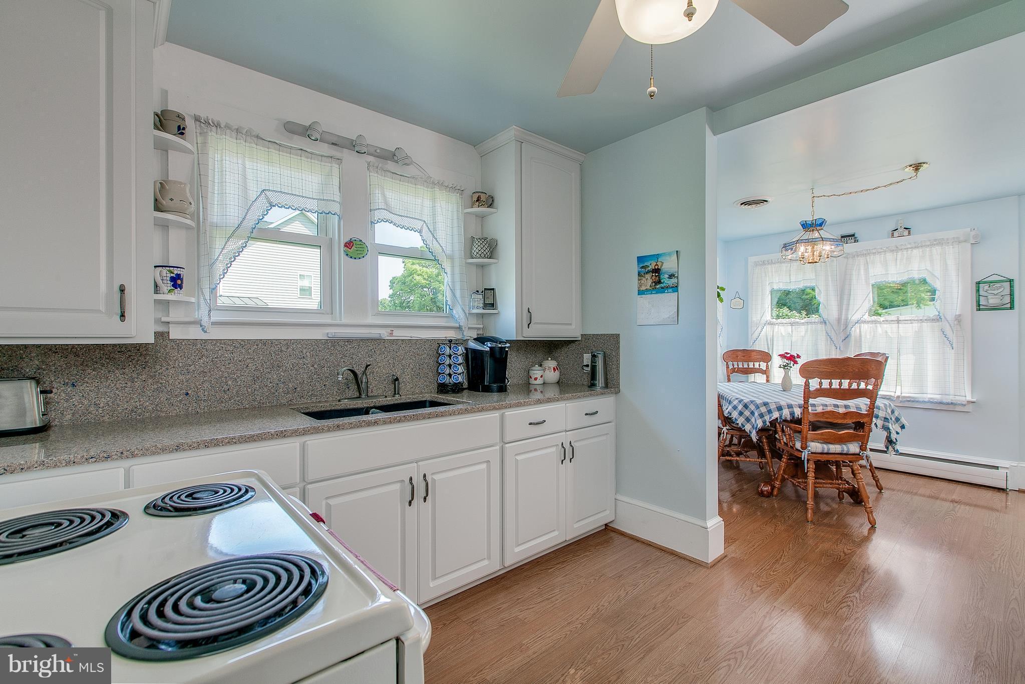 8317 Myersville Road Middletown, MD 21769 - Photo 16 of 30 a kitchen with a stove a refrigerator and a dining table with wooden floor