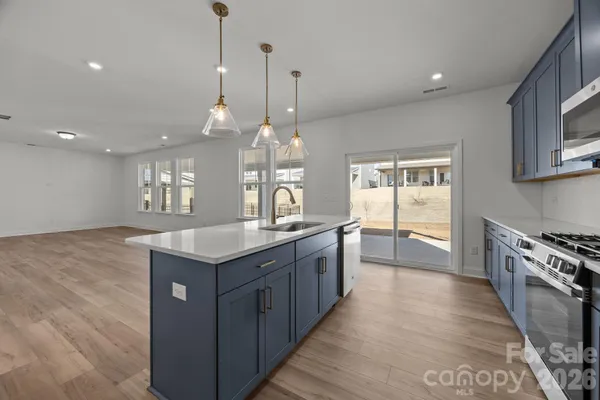 a kitchen with stainless steel appliances granite countertop a sink a stove and a wooden floors