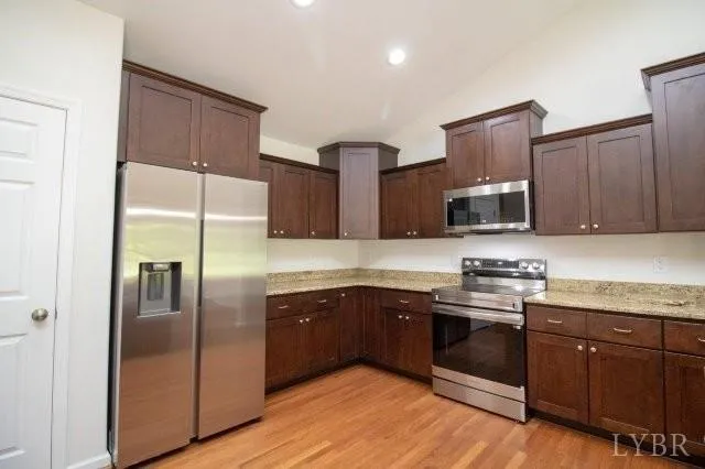 a kitchen with stainless steel appliances granite countertop a refrigerator and a stove top oven