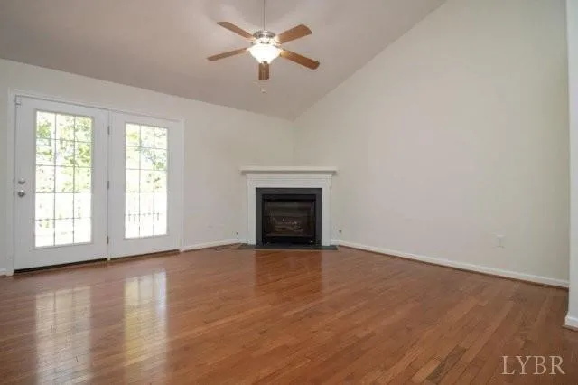 an empty room with wooden floor chandelier fan and windows