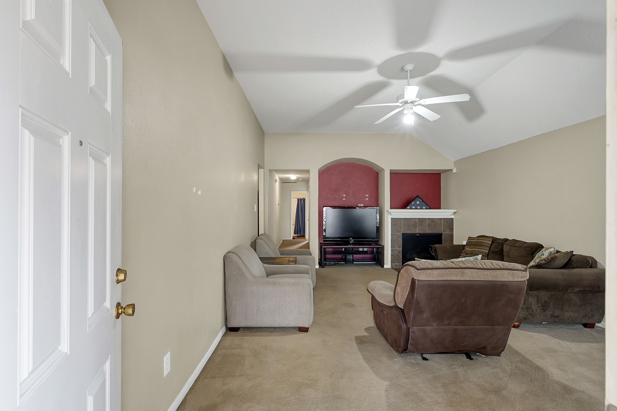 22518 Goss Spring Court Spring, TX 77373 - Photo 16 of 19 This is a cozy living room with neutral walls and carpet, featuring a ceiling fan and a fireplace with a TV nook. The space is furnished with comfortable sofas and chairs, creating a welcoming atmosphere.