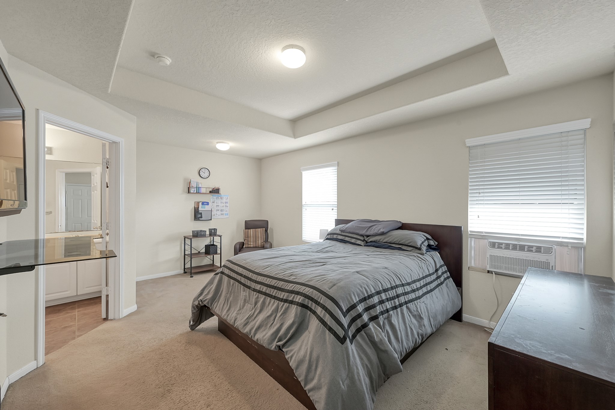 22518 Goss Spring Court Spring, TX 77373 - Photo 10 of 19 This bedroom features a cozy layout with a large bed, neutral walls, and carpeting. It includes a window with blinds, a small desk, and an air conditioning unit. An adjoining bathroom adds convenience.