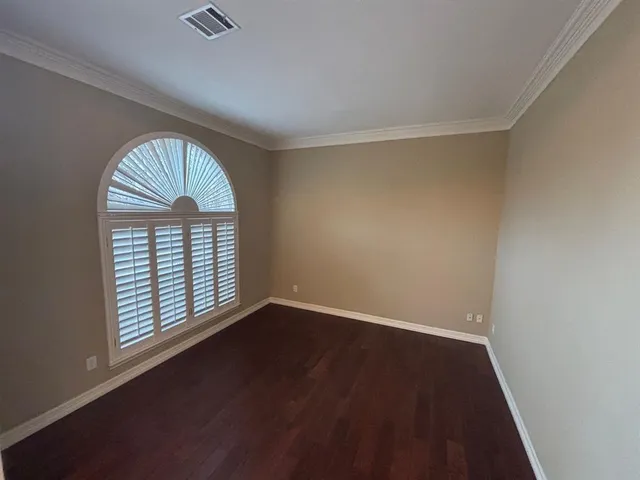 an empty room with wooden floor a exposed radiator and a window