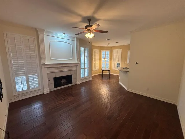 a view of a livingroom with wooden floor a ceiling fan and windows