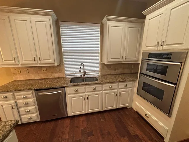 a kitchen with granite countertop white cabinets and stainless steel appliances